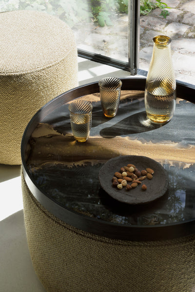 Tray on top of an ottoman with a carafe of water and two glasses - a plate of almonds and macadamia nuts are beside them