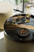 Tray on top of an ottoman with a carafe of water and two glasses - a plate of almonds and macadamia nuts are beside them