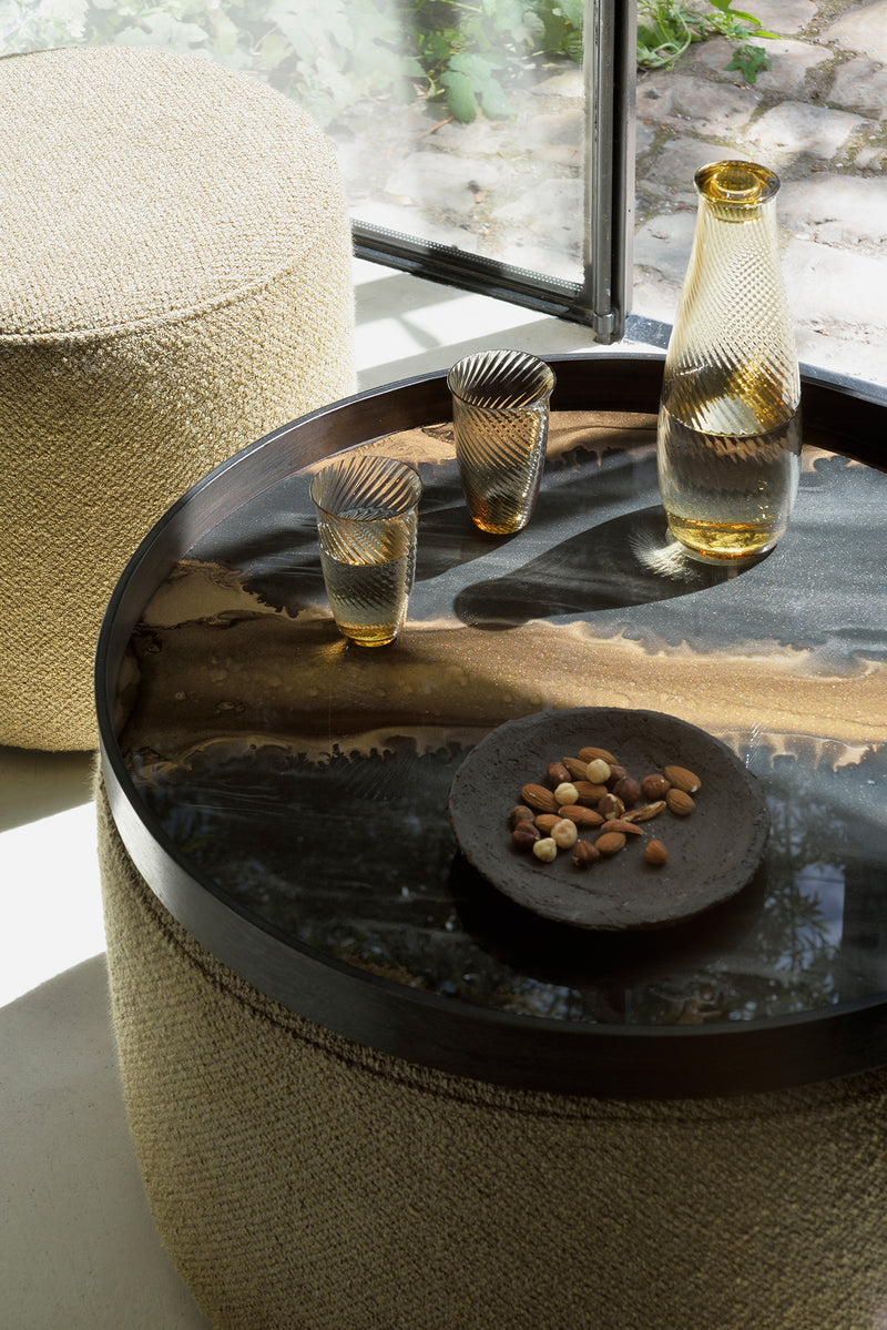 Tray on top of an ottoman with a carafe of water and two glasses - a plate of almonds and macadamia nuts are beside them