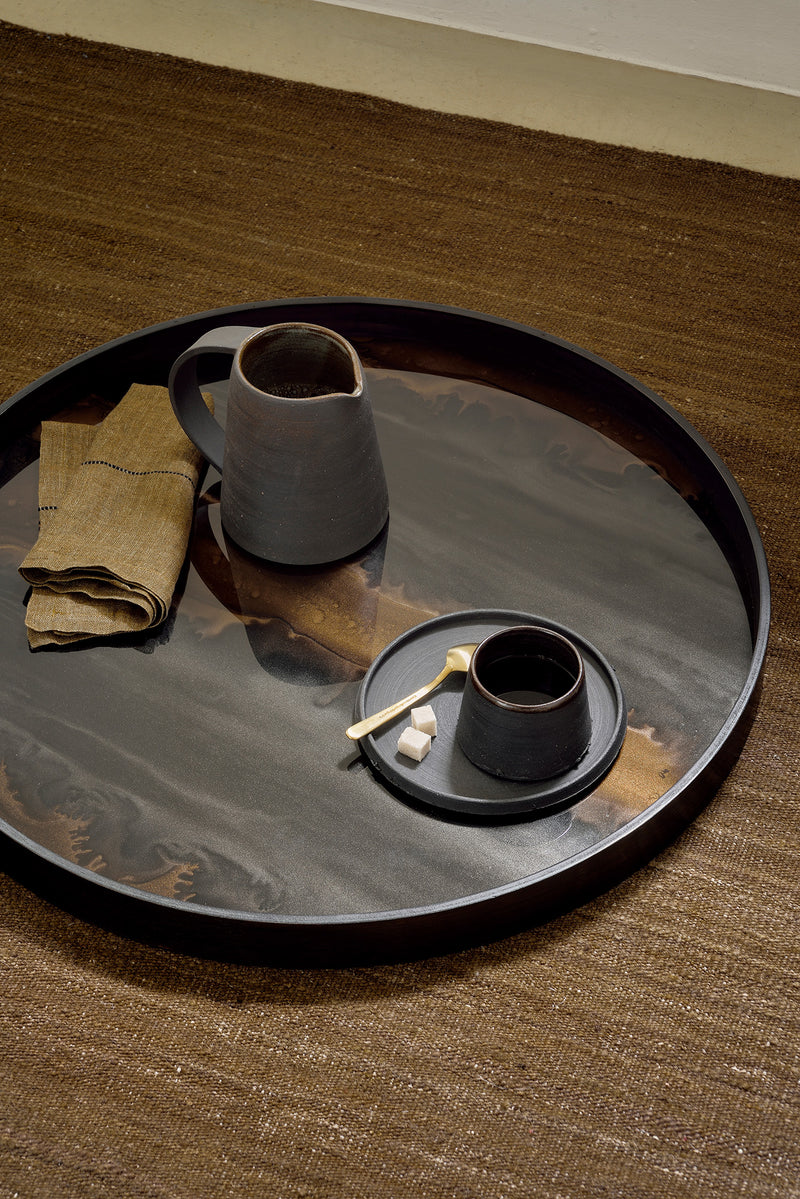 Tray on a rug with a ceramic coffee set on top. A mustard napkin accents the style
