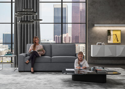 American Leather soft grey colored Olson Sofa Sleeper with mother reading on sofa and daughter coloring at the coffee table in front. Both mother and daughter are enjoying themselves.