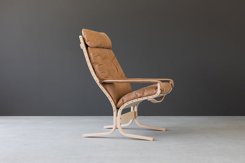 Siesta Classic high back with arms in vintage natural leather on oak base with a soft background in grey and white horizon GALLERY